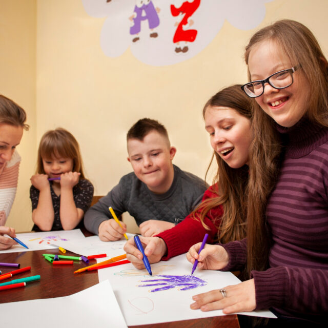 happy girl with down syndrome posing while drawing